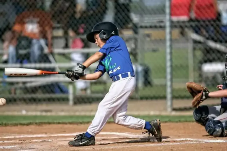 Young boy hitting a baseball with a composite baseball bat.