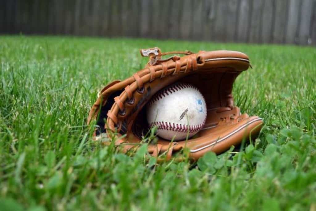 Baseball glove with baseball inside lying on the grass.