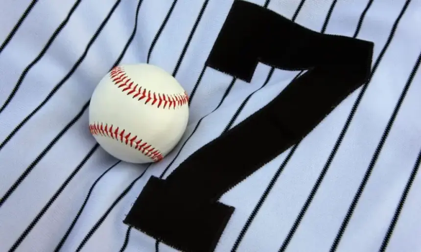 Baseball jersey with baseball lying on it.