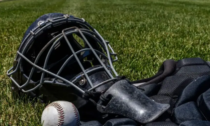 Dirty baseball catcher gear lying on the grass.