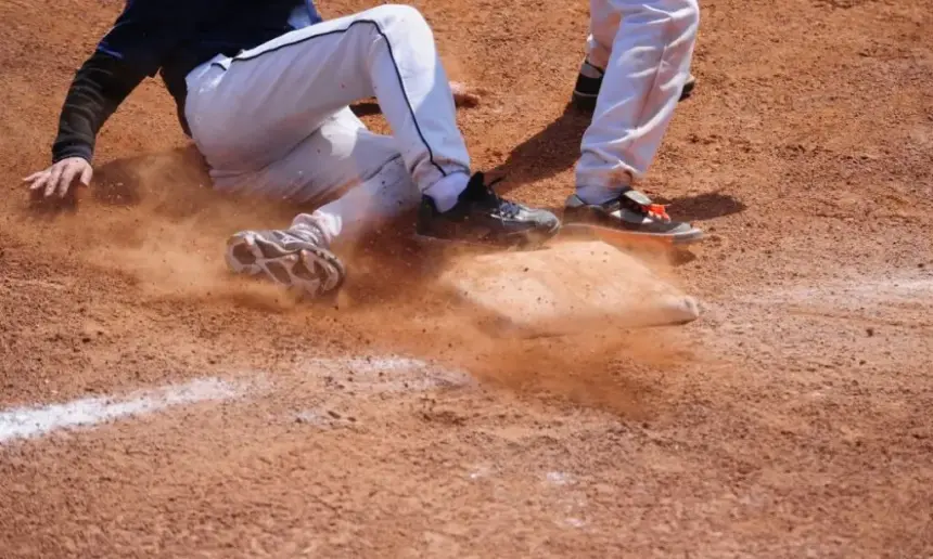 Baseball player in long pants sliding into base.