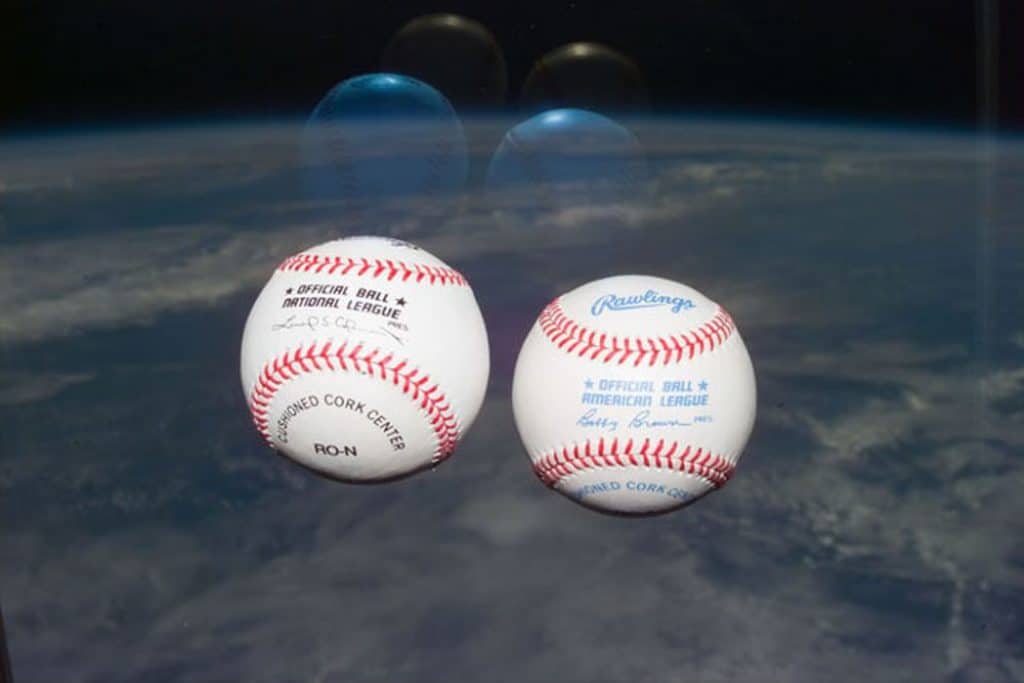 Two different baseballls lying on the ground.