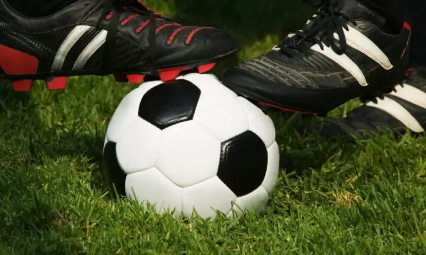 Two soccer cleats stand on a ball.