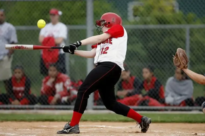 Male softball player batting a softball.