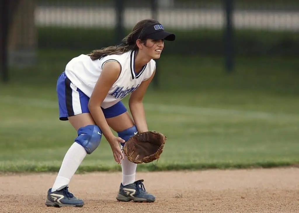 Female softball catcher in waiting position.