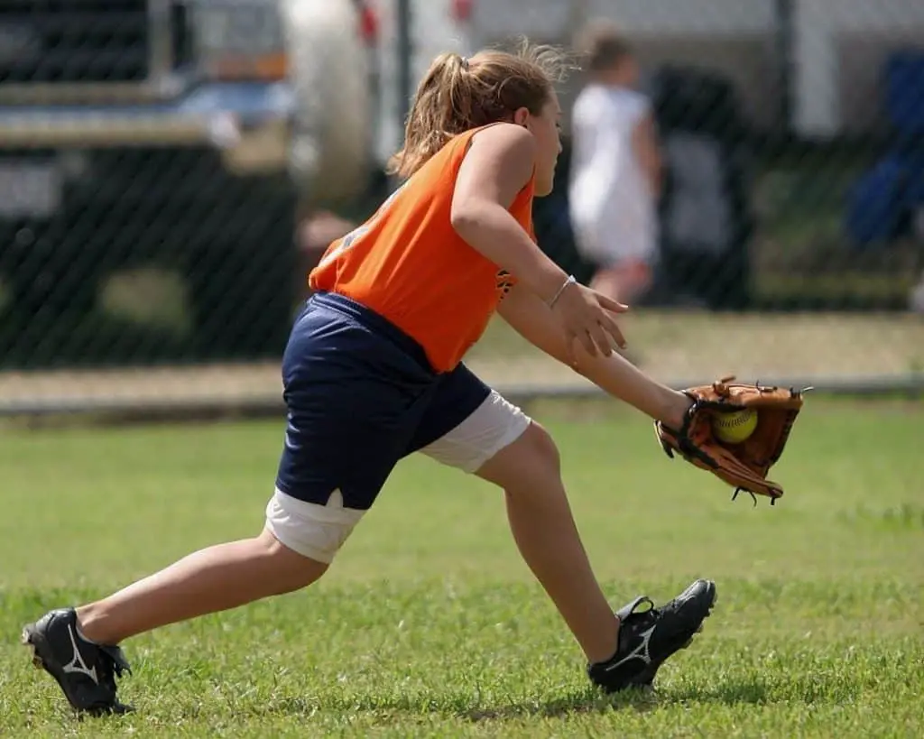 Female player catching a softball with her glove.