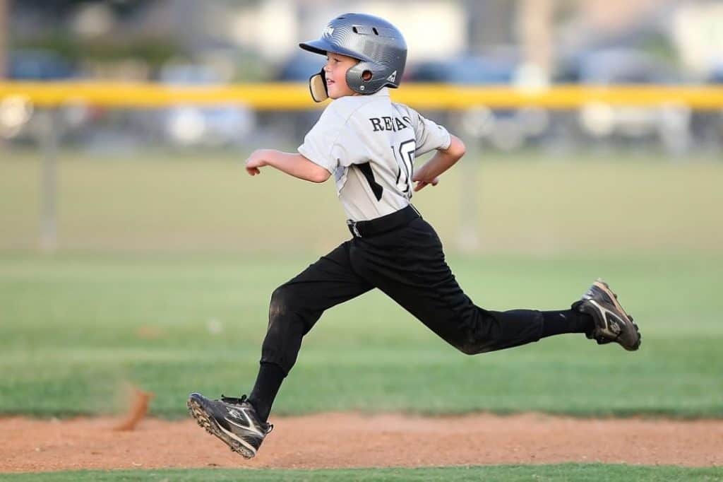 Young kid running on the turf with baseball cleats.