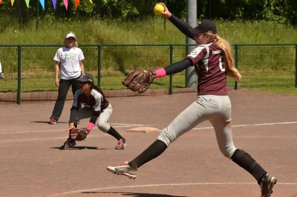Female softball player pitching a ball overhand.
