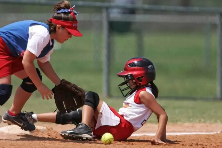 Young female softball player sliding into the base.