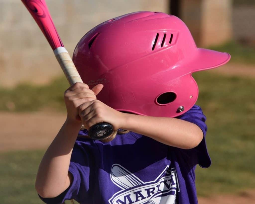 Child with pink helmet and pink softball bat.