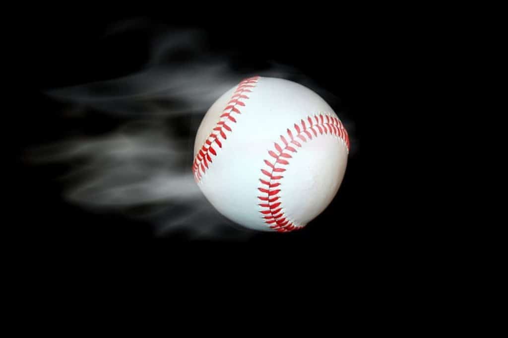 White baseball flies at high speed on a black background.