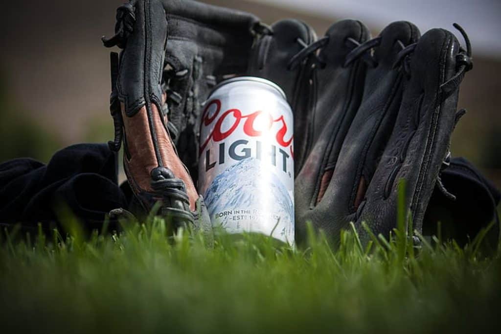 Beer can and baseball glove in the grass.
