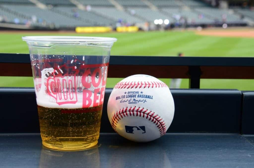 Beer mug and baseball ball with baseball field in background.