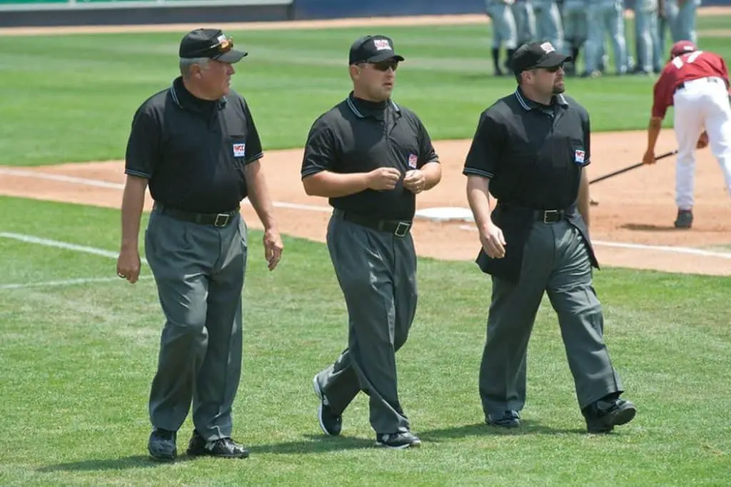 Three baseball umpires walking onto the field.