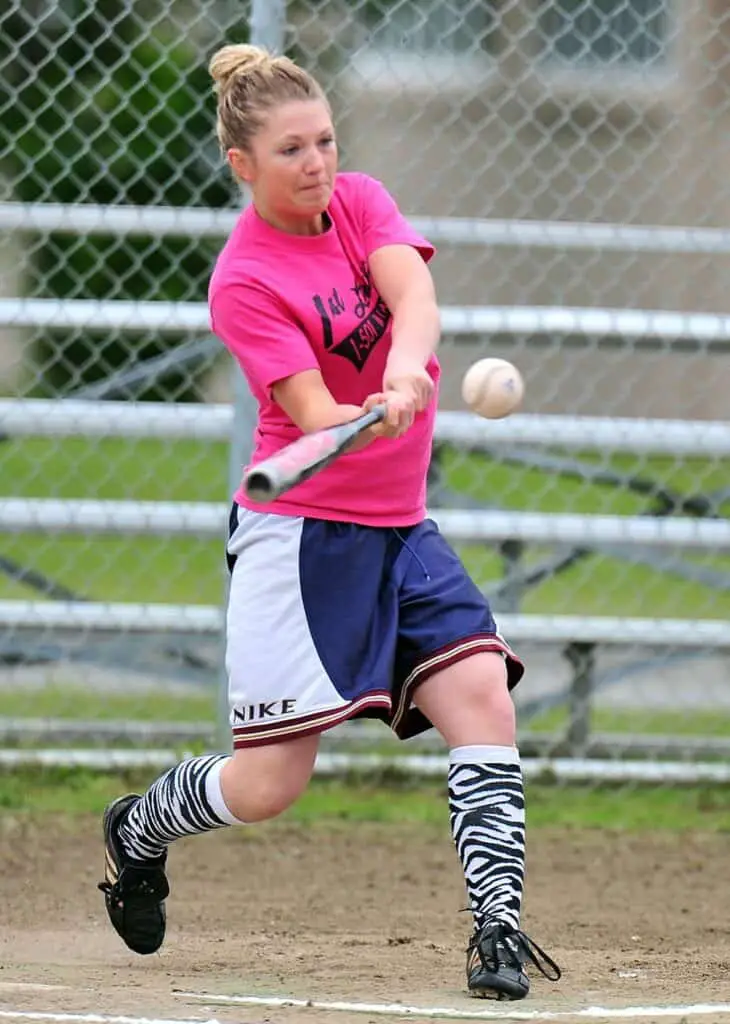 Female baseball batter hittng a ball.