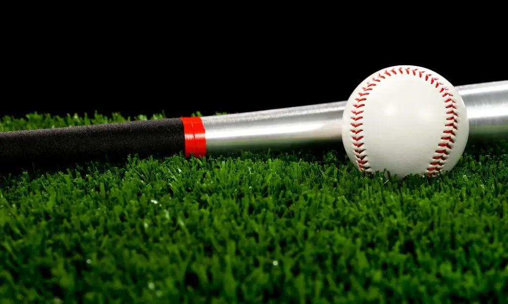 Aluminum baseball bat and baseball lie on the grass.